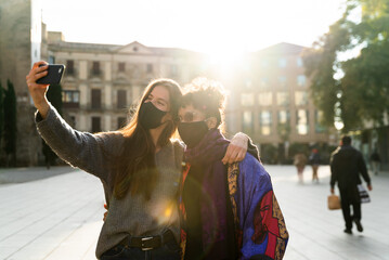 Two young woman taking a selfie using a protective face mask during the covid-19.