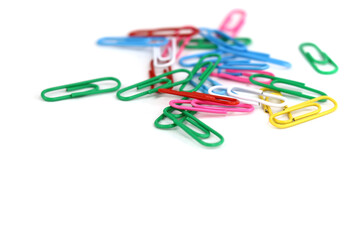 colored paper clips scattered on a white background
