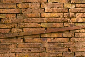 old brick wall texture with a rusty piece of iron running through it