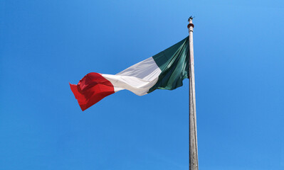 Italian flag fluttering on blue sky
