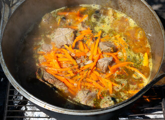 Cooking traditional oriental pilaf in a cauldron over a fire.