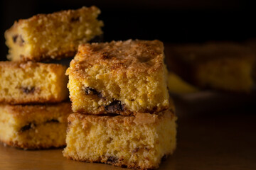 Close-up of a vanilla cake with chocolate chips cut into cubes on dark background