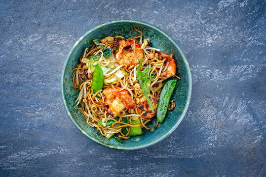 Modern style traditional Thai phak kung curry with barbecue king prawns and noodles as top view in Nordic design bowl with copy space