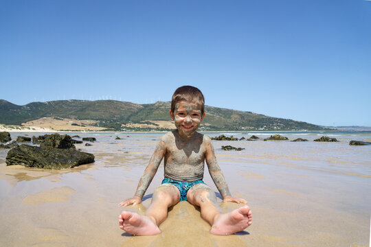 Child with the body slathered in mud on a beach