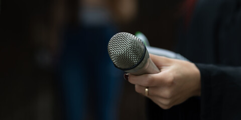 Journalist in action at news conference, writing notes, holding microphones