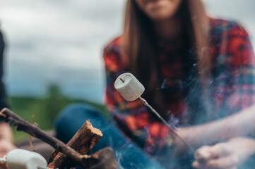 Obraz na płótnie Canvas Marshmallows on a stick above the camping fire