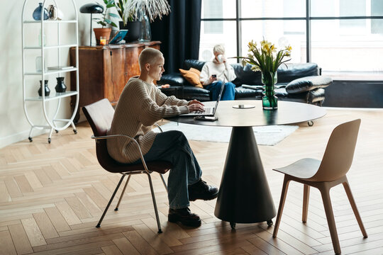 Young content woman using laptop at home office.