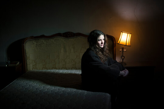 Young woman sitting in the border of the bed