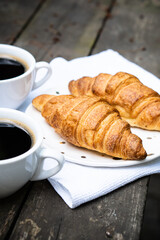 Coffee and croissants on old rustic wooden table