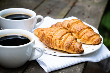 Coffee and croissants on old rustic wooden table