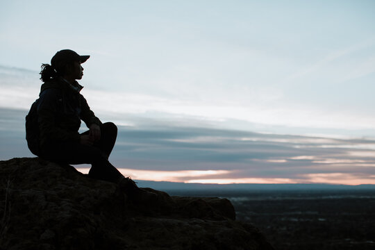 Silhouette of a Woman Sitting after a Hike at Sunset