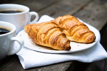 Coffee and croissants on old rustic wooden table