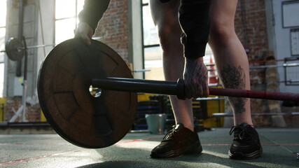 A strong athletic woman is preparing a barbell for her workout