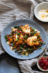 Grilled halloumi cheese with roasted chickpeas, broccollini, tahini sauce and pomegranate
