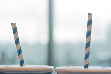 Blue and white striped organic paper straw in blue paper cup. Recycle concept.