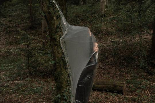 Young Woman Dancing In The Forest And Trapped In A Plastic Sheet