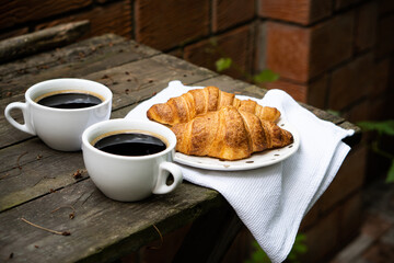 Coffee and croissants on old rustic wooden table