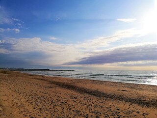 Fototapeta na wymiar cielo azul con nubes blanquecinas y arena de playa rojiza