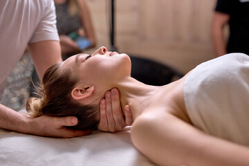 Side view on professional cropped therapist doing healthy massage on neck and shoulders to female...
