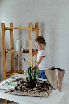 Child adding soil into pot with flowers