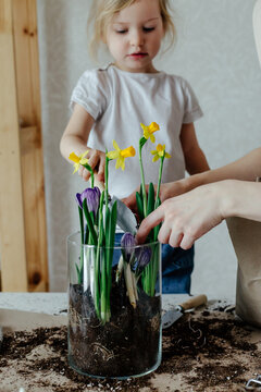 Child adding soil into pot with flowers