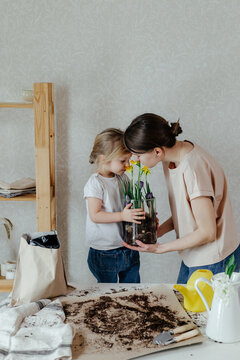 Mother and daughter smelling flowers in glass pot