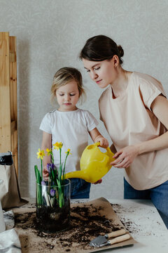 Mother and daughter watering flowers in glass pot