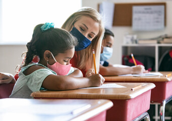 School: Teacher With Mask Helps Student With Math Sheet