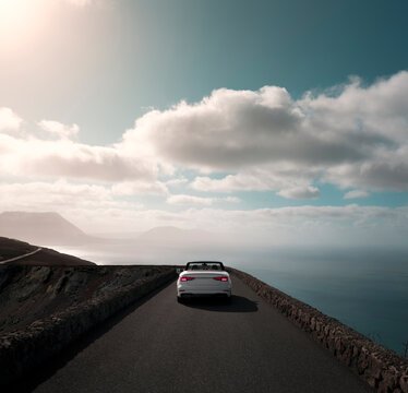 White car driving around the cliffs