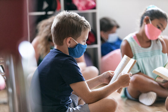 School: Students Wearing Face Masks Sit On Floor For Reading Tim