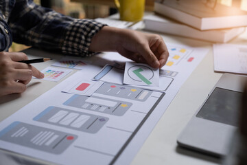 A close-up of an ux ui developer and an ui designer working on a mockup icon interface for a mobile app.