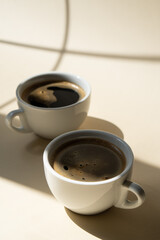 Two cups of coffee on beige studio background