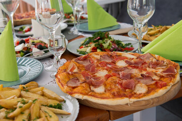 Big dinner with pizza, salad and fried potatoes. Birthday, Christmas, New Year, festive dinner, a table, gathering or celebration concept.