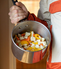Homme avec une casserole dans la main remplie de pommes de terres et autres légumes cru