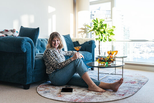 Stylish young woman enjoying a cocktail drink in living room 