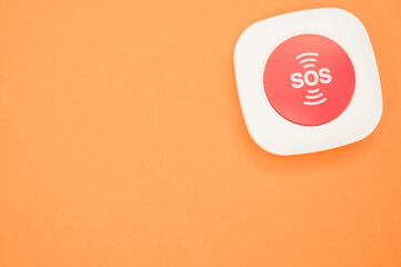 Top view of an SOS button on an orange surface
