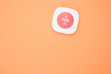 Top view of an SOS button on an orange surface
