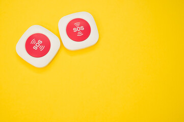 Top view of two SOS buttons on a yellow surface