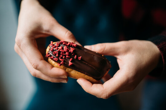 Person holding sweet pastry with chocolate and freeze-dried raspberries
