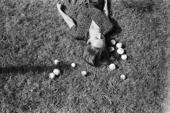 A film portrait of a beautiful woman with apples lying on a ground