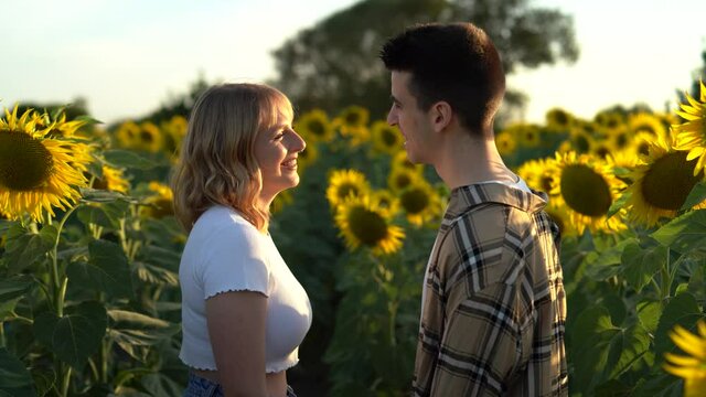 Pareja de chico y chica en campo de giraoles sonriendo y pasandolo bien