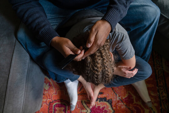 Faceless image of dad removing child's cornrows