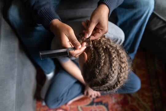 Top down view of dad using comb to remove boy's cornrows