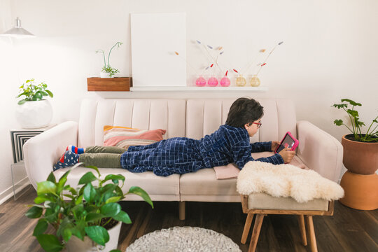 Boy with robe using iPad while relaxing on couch