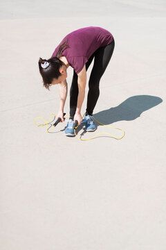 Sport young woman tyeing her shoes