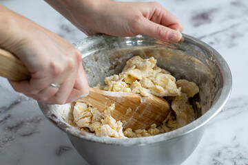 aperçus des mains d'une femme en train de mélanger une pâte fraichement préparée avec des...