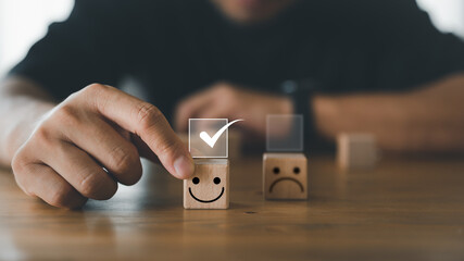 Businessman make a choice and giving rating with happy icon, customer hand choose smiley face icon on wood cube. Service rating, satisfaction and customer experience concept.