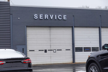 Closeup view of two overhead garage doors with the word service on the gray wall above one of the...