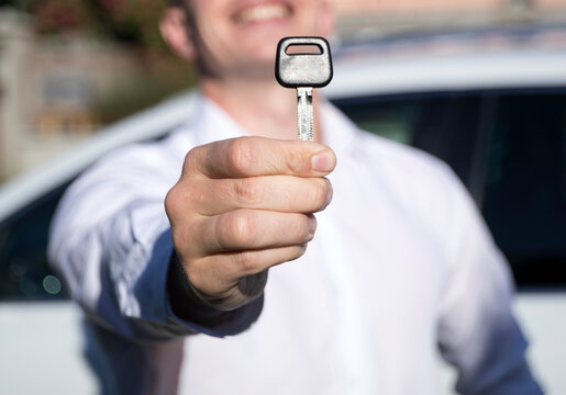 Male holding car keys with car on background
