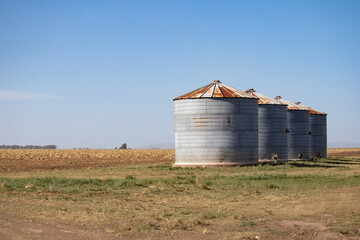 silos in a field on sunny day with light blue sky